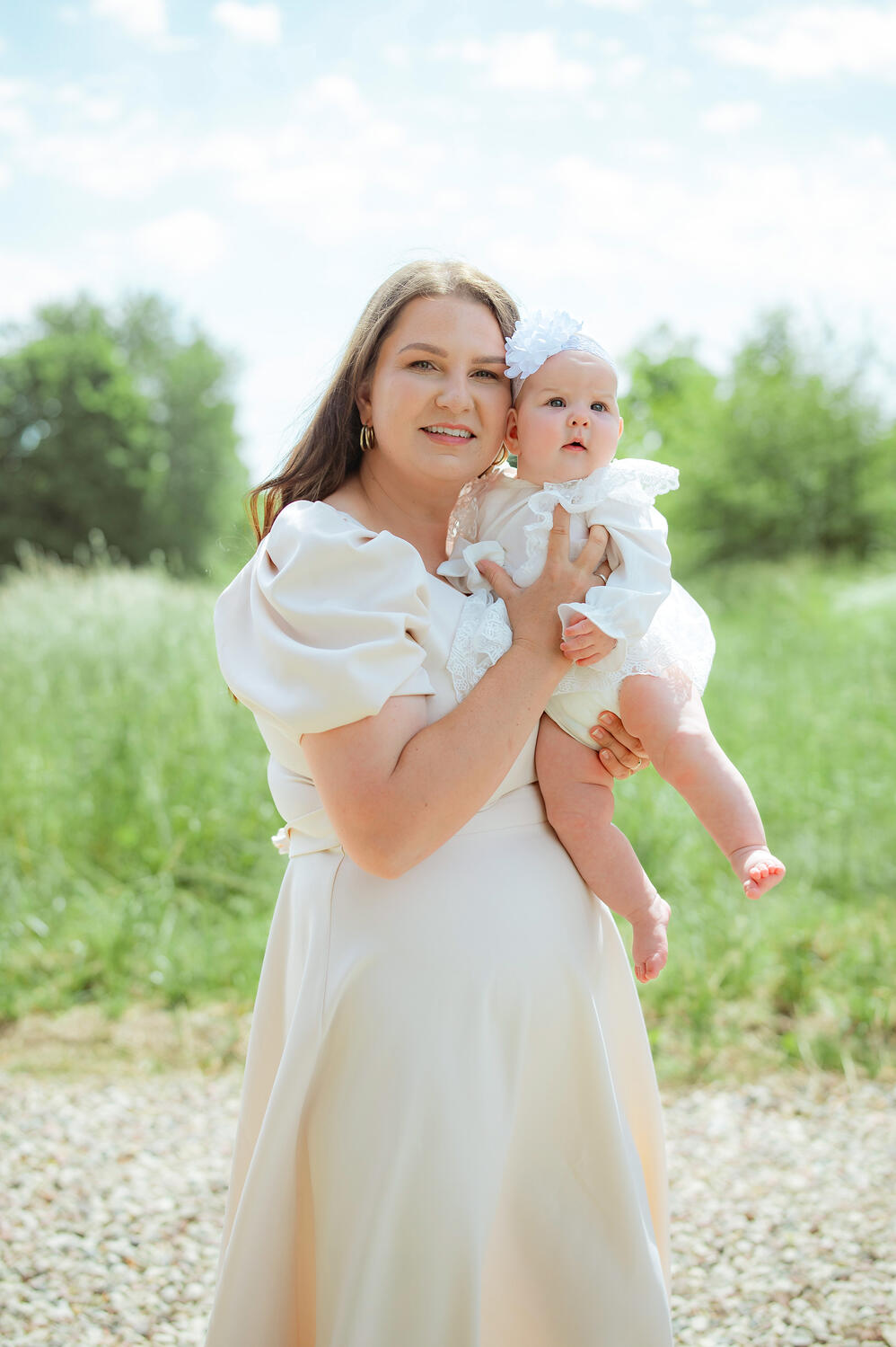 Mamos ir dukros portretas Mama apkabinusi dukrą pozuoja krikštynų fotografei