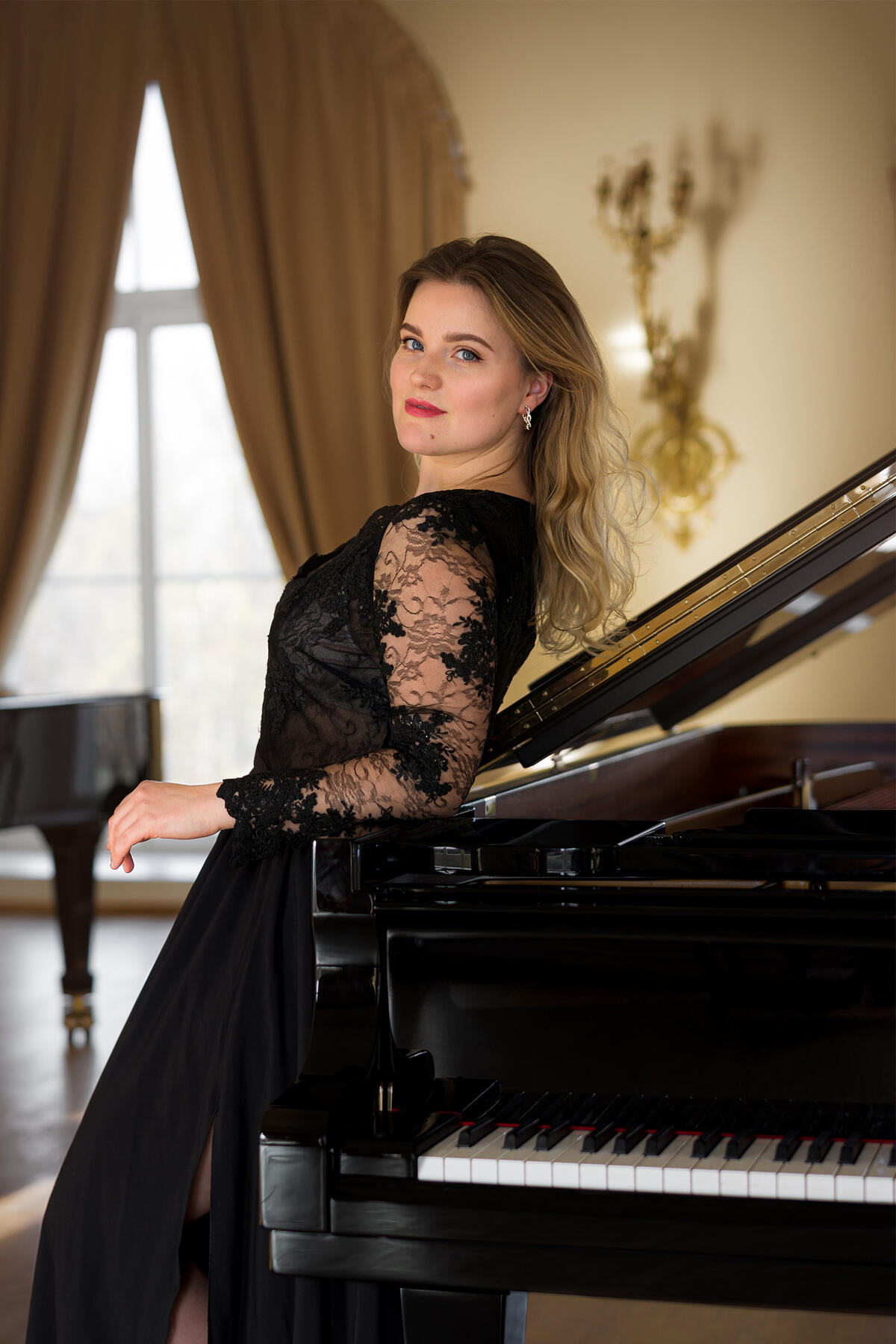 Asmeninė muzikantės fotosesija Šviesiaplaukė mergina pasirėmusi į pianiną - profesinė fotosesija koncertų afišoms - portretas