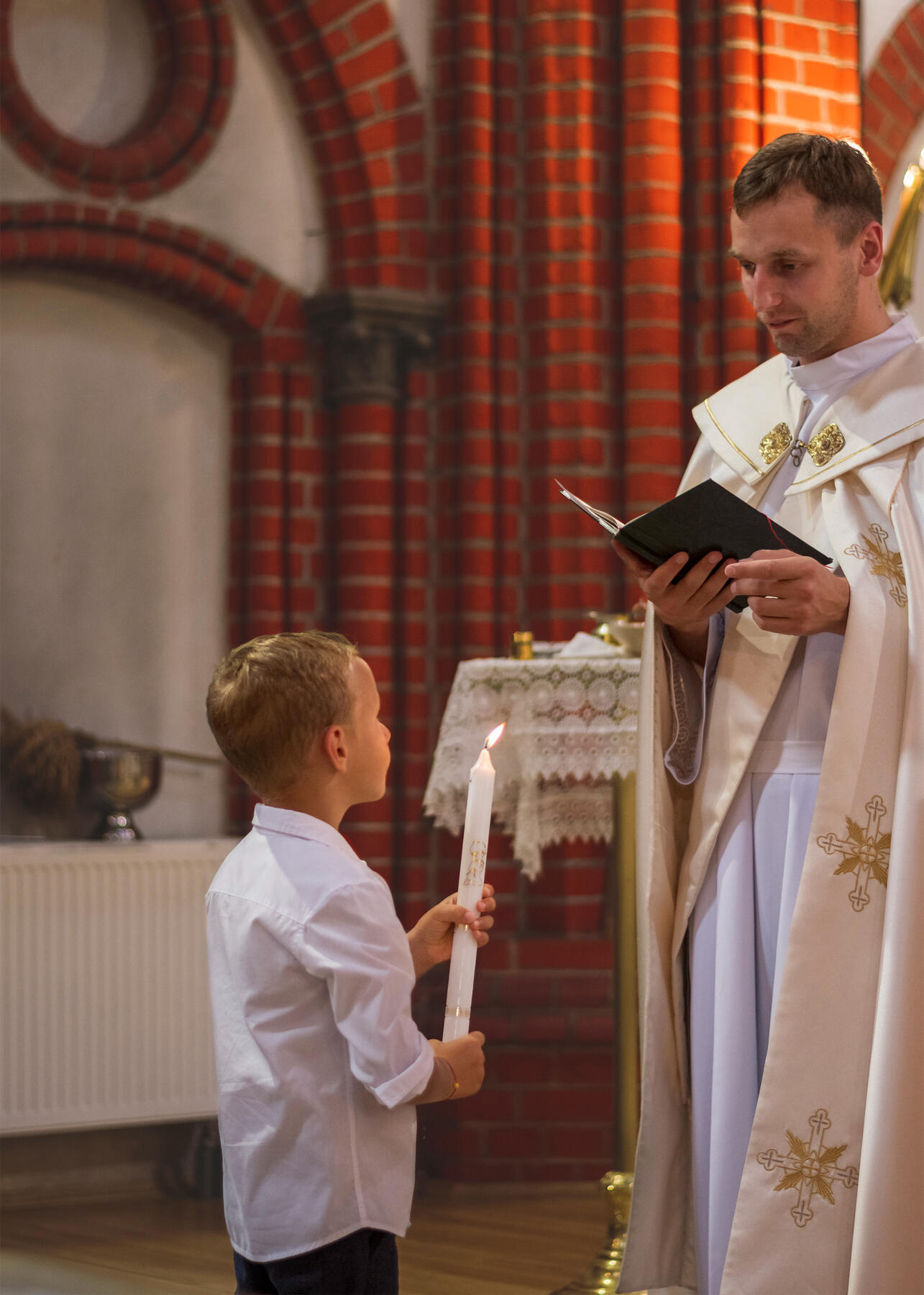 Untitled Krikšto ceremonija, kunigas skaito iš knygos, vaiko laiminimas