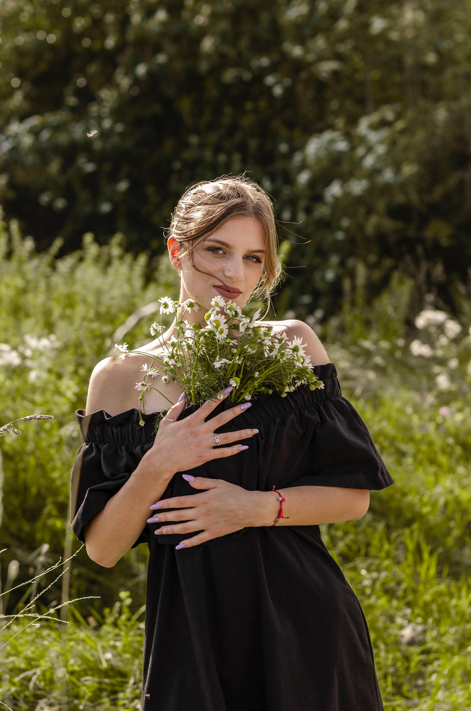 Mergina pozuoja su lauko gėlėmis, portretas