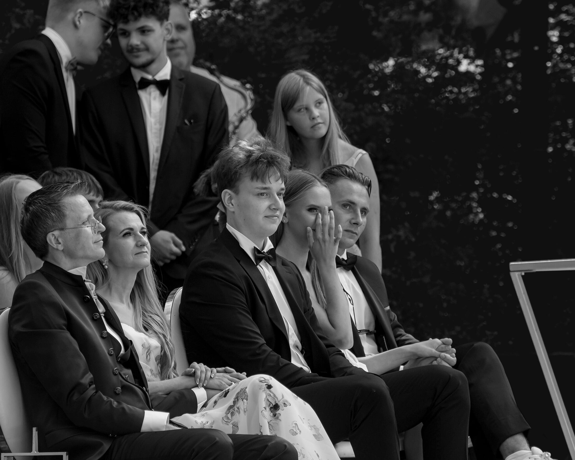 Vestuvių ceremonija, artimieji ir draugai iš laimės susijaudine, šnabždasi ir braukia ašaras.