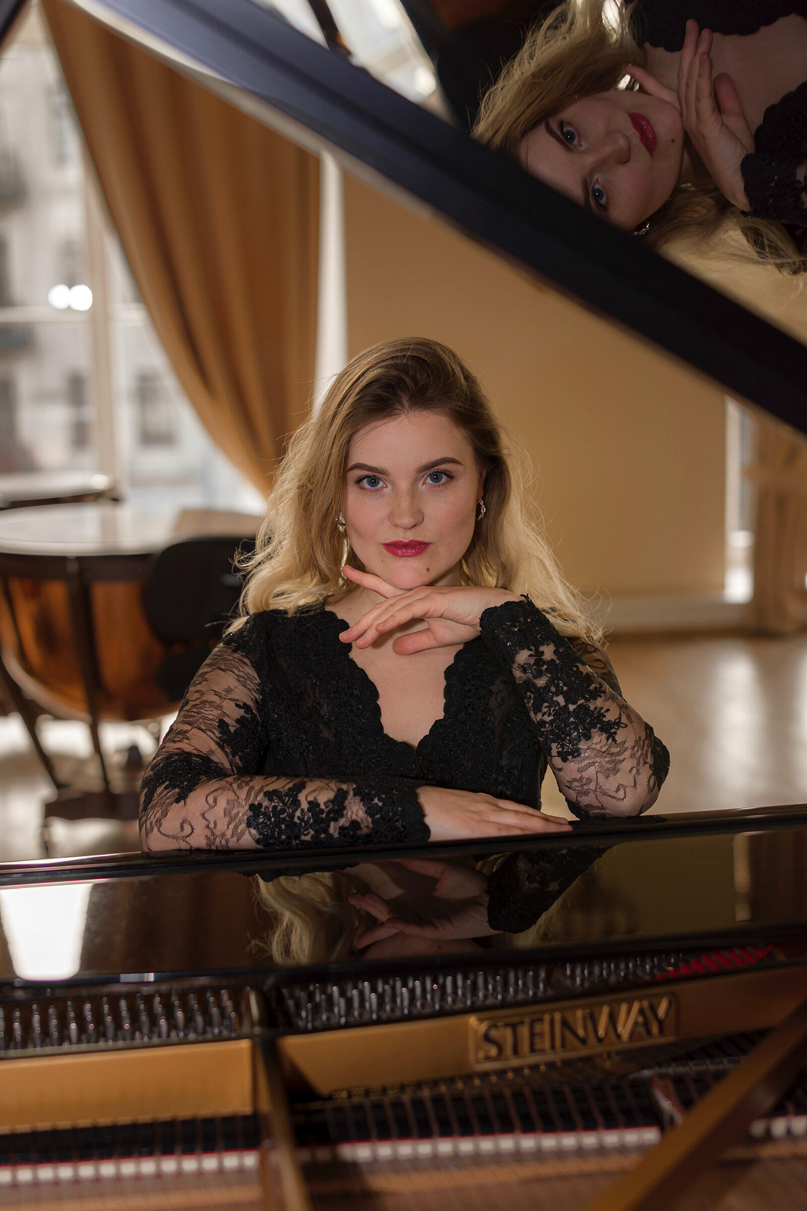 Pianistės asmeninė fotosesija Pianistės portretas - muzikantė sėdi prie steinway fortepijono pasirėmusi ranka, žvilgsnis į objektyvą