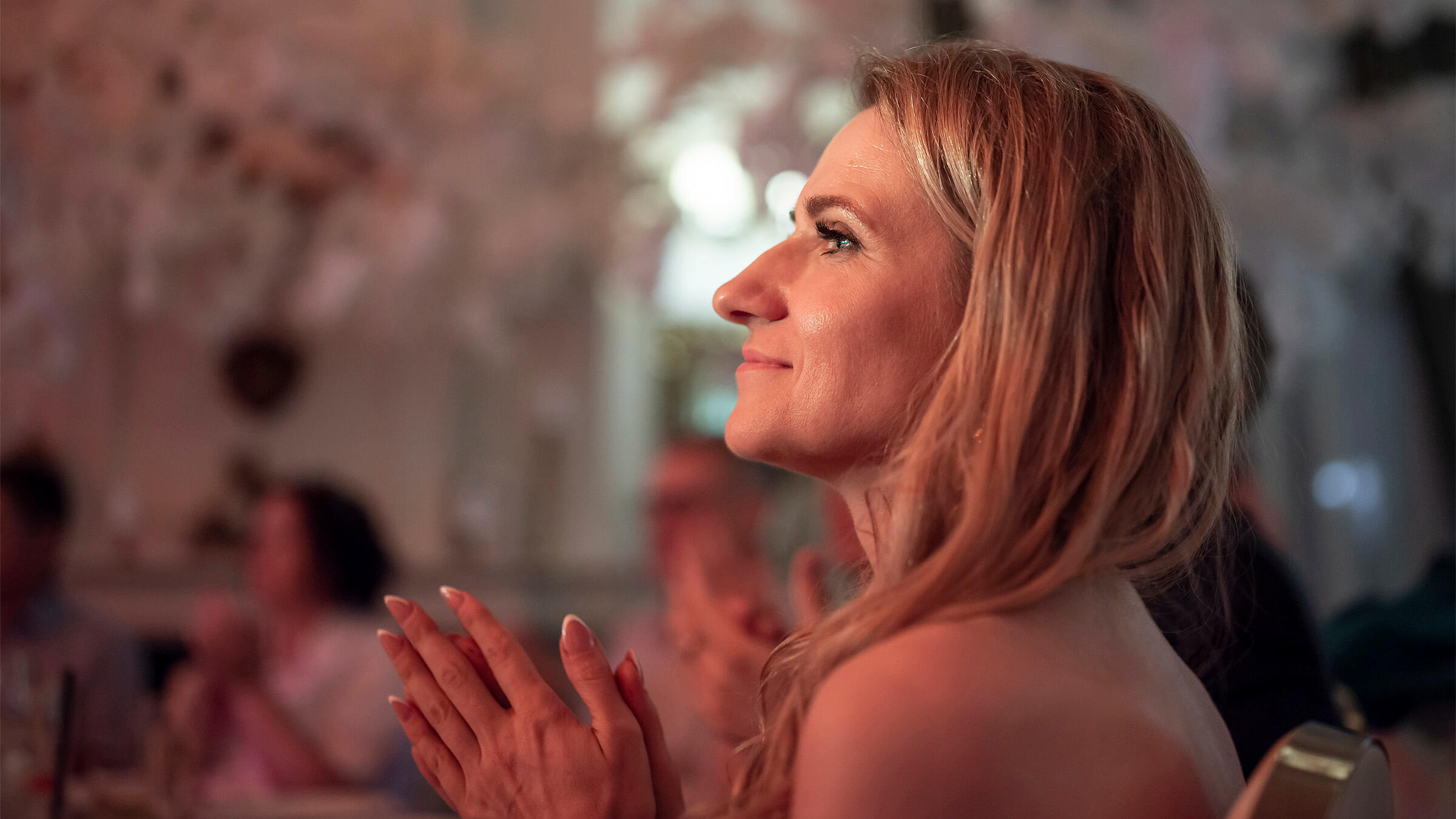 Dainininkų mama ir žmona švelniai šypsosi ir ploja dainininkams